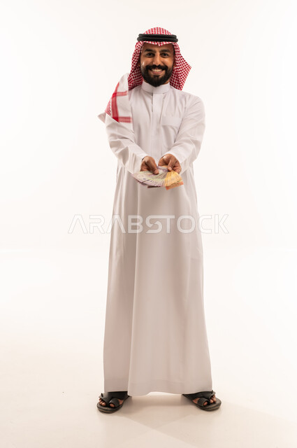 رجل سعودي يمسك أوراقاً نقدية من الريال السعودي