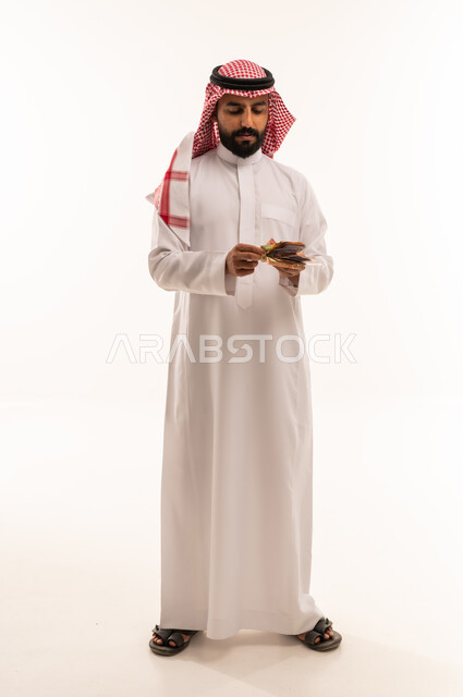 رجل سعودي بالزي التقليدي يعد النقود الورقية