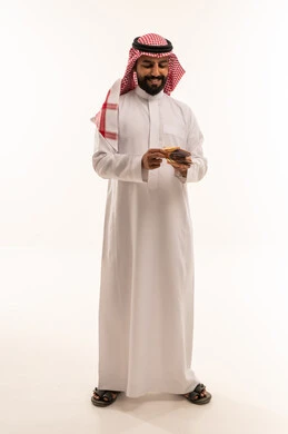Saudi Man in Traditional Thobe Counting Riyal Banknotes