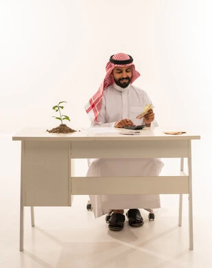 Saudi Businessman with Money and Plant at Desk