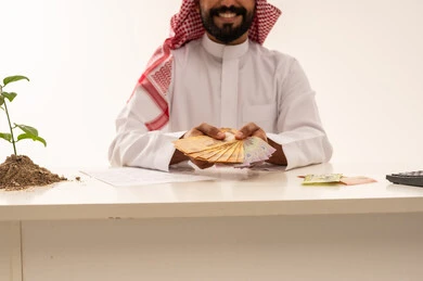 Saudi Businessman Holding Riyal Banknotes at Office Desk