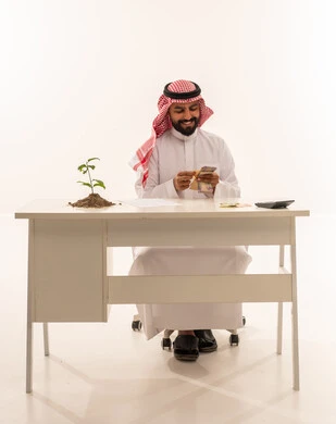 Saudi Businessman Counting Riyals with Growing Plant