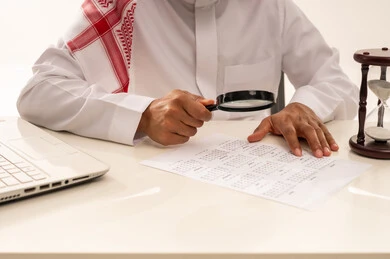 Saudi Businessman Inspecting Calendar with Magnifying Glass