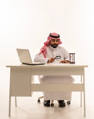 رجل أعمال سعودي على المكتب يفحص الأوراق بالعدسة