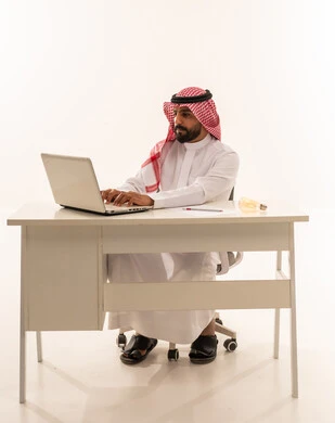 رجل سعودي يعمل على لاب توب في مكتب أبيض