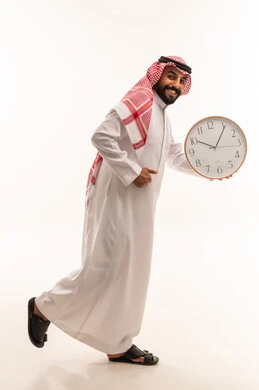 رجل سعودي بالثوب التقليدي يركض ممسكاً بساعة حائط