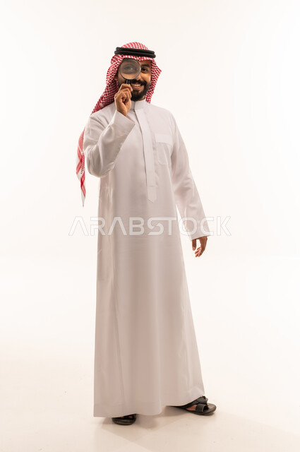 رجل سعودي يحمل عدسة مكبرة على خلفية بيضاء