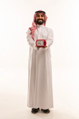 رجل سعودي بالثوب التقليدي يحمل ساعة منبه