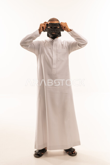 رجل سعودي بالثوب الأبيض يحمل قناع وجه أسود