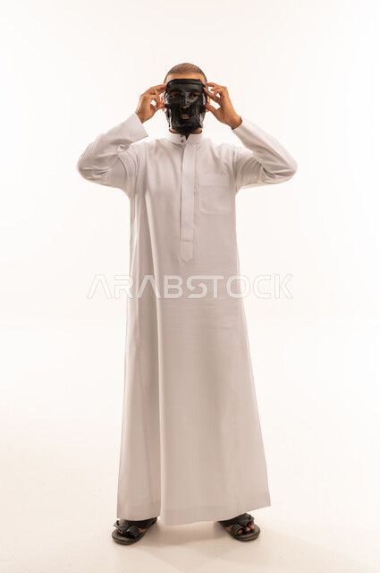 Saudi Man in White Thobe Applying Black Face Mask