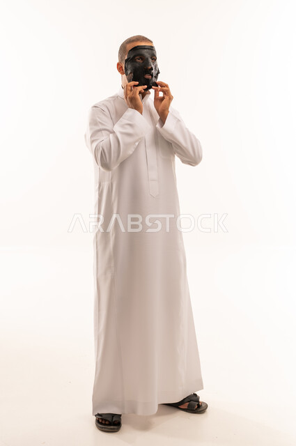 رجل سعودي بالثوب الأبيض يرتدي برقعاً تراثياً