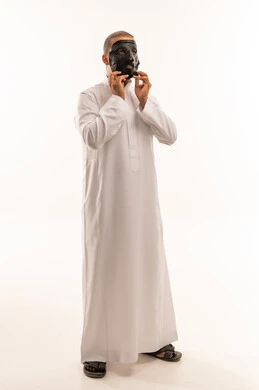 رجل سعودي بالثوب الأبيض يرتدي برقعاً تراثياً