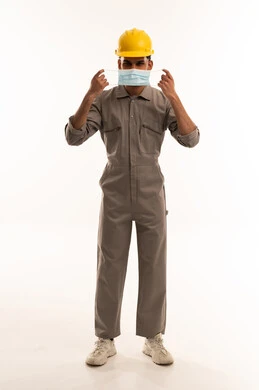 عامل يرتدي خوذة وبدلة عمل وكمامة طبية واقية