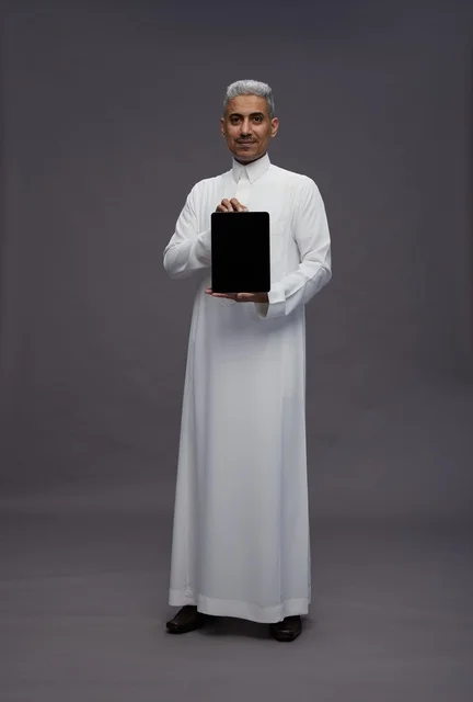 رجل سعودي يحمل جهاز لوحي شاشة سوداء في استوديو