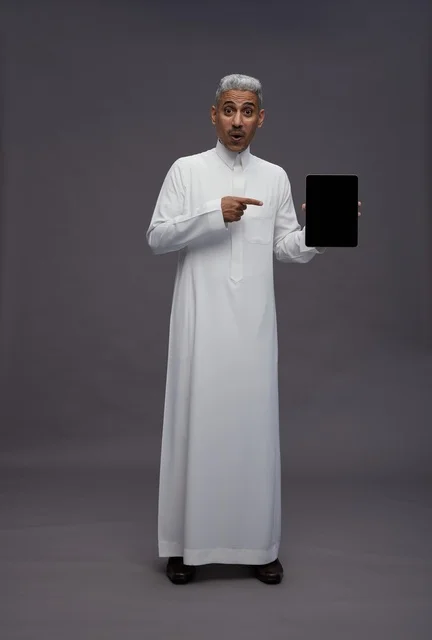 رجل سعودي يشير إلى شاشة جهاز لوحي في الاستوديو