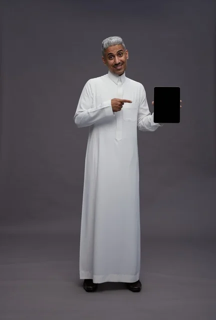 رجل سعودي بالثوب التقليدي يمسك بجهاز لوحي رقمي