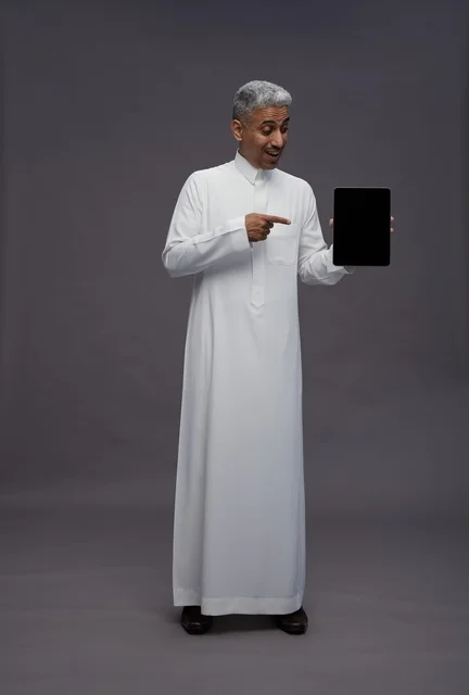 رجل سعودي يحمل جهاز لوحي رقمي في الاستوديو