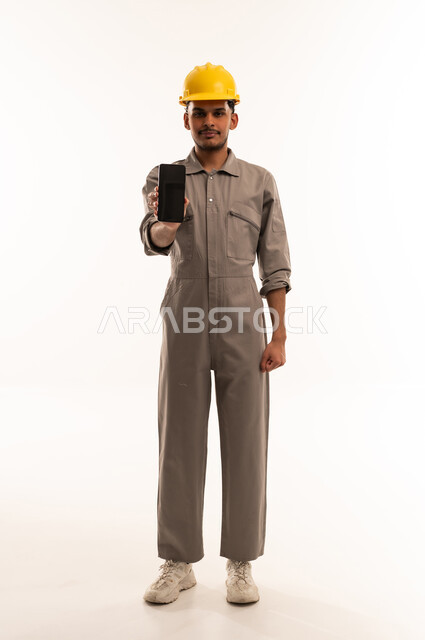 عامل بناء سعودي يمسك هاتف جوال بخلفية بيضاء
