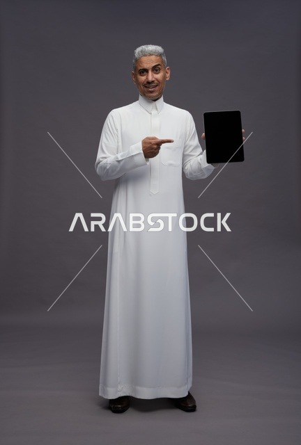 Saudi Man in Traditional White Thobe Pointing at Tablet