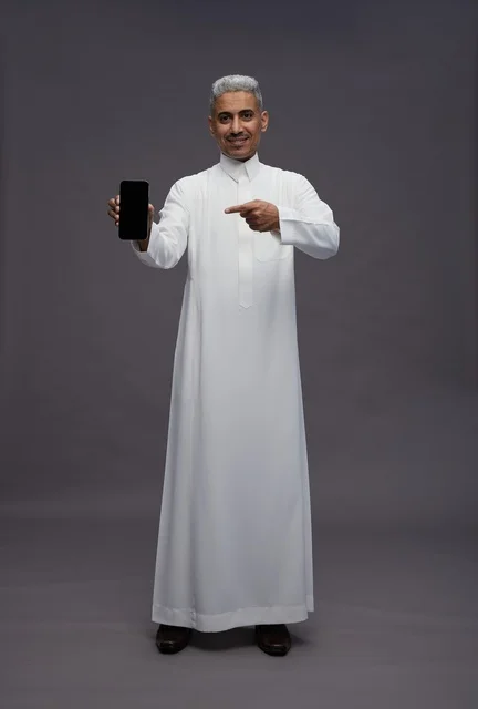 Saudi Man Pointing at Smartphone on Grey Background