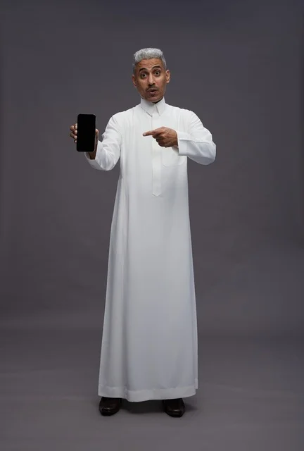 Saudi Man in White Thobe Holding Smartphone Surprised