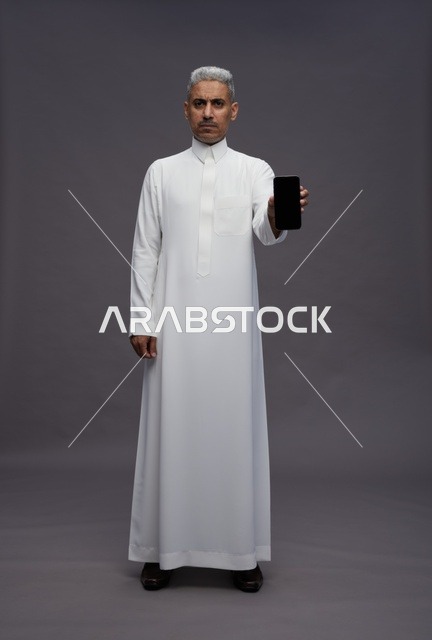 Saudi Man Holding Smartphone on Grey Background