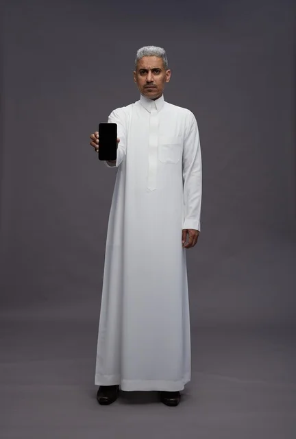 Saudi Man Holding Smartphone on Grey Studio Background