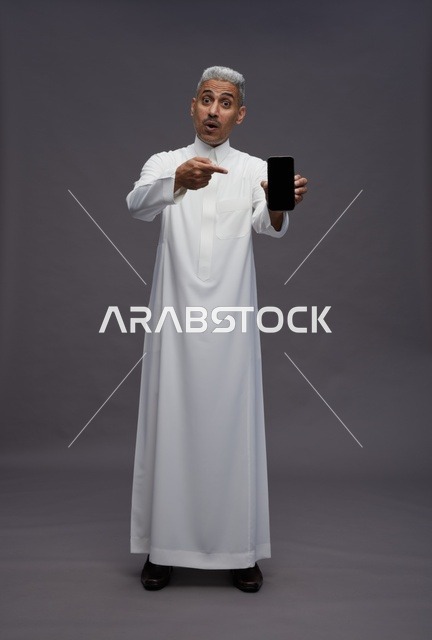 Saudi Man Pointing at Smartphone Screen in Studio