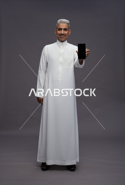 رجل سعودي يمسك بهاتف ذكي في الاستوديو