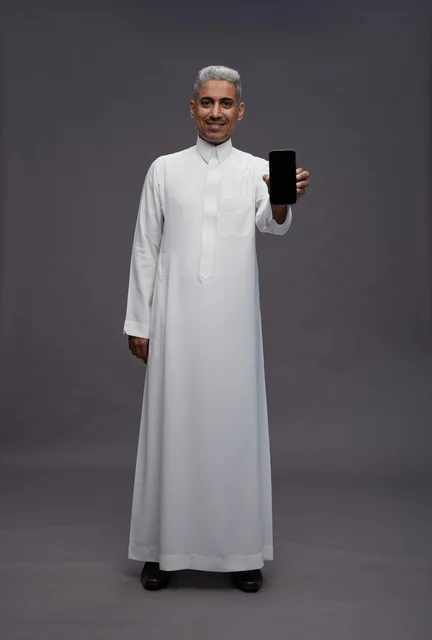 رجل سعودي يمسك بهاتف ذكي في الاستوديو