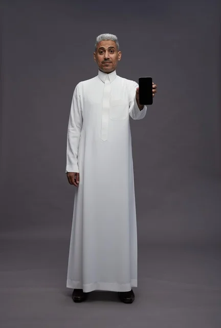 رجل سعودي يعرض هاتف ذكي بخلفية رمادية
