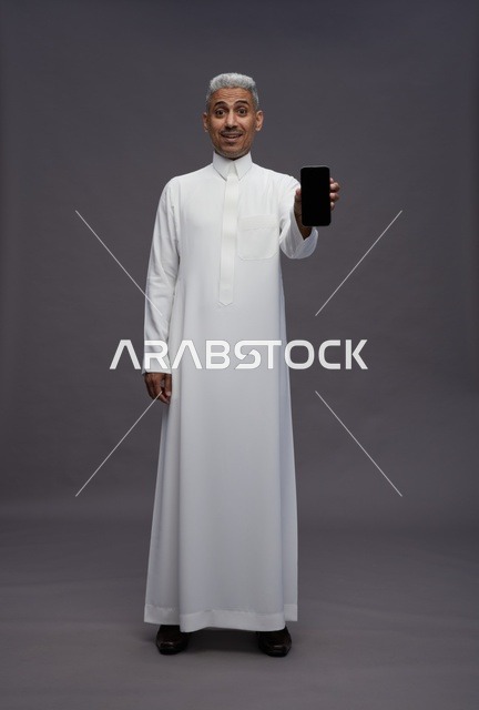 Saudi Man in Thobe Holding Smartphone in Studio