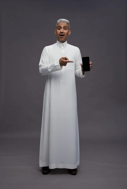 Saudi Man Pointing at Smartphone Screen on Grey Background