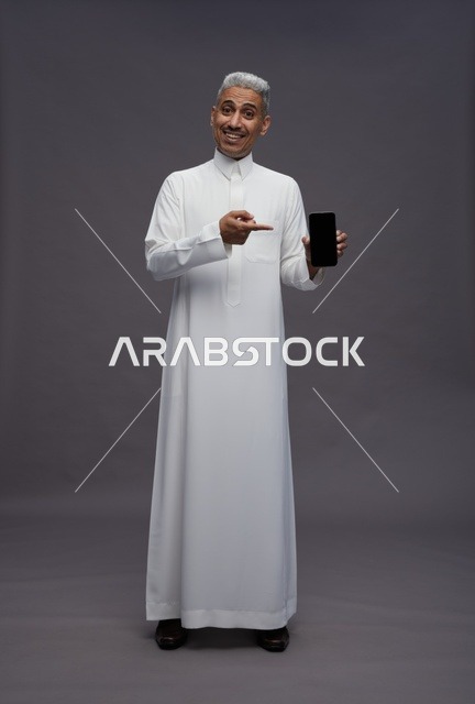 Saudi Man Holding Smartphone on Grey Background