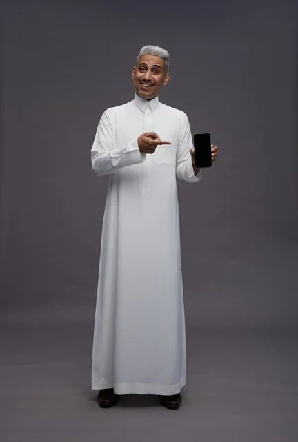 رجل سعودي يحمل هاتف ذكي خلفية رمادية