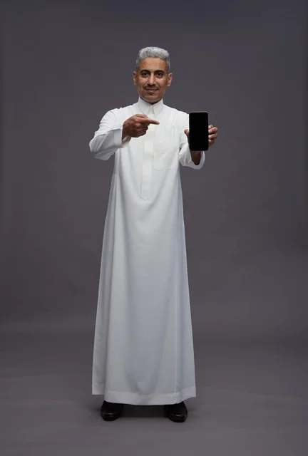 Saudi Man Holding Smartphone on Grey Background