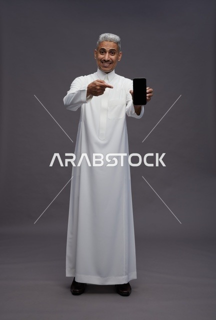 Saudi Man Pointing at Smartphone on Grey Background