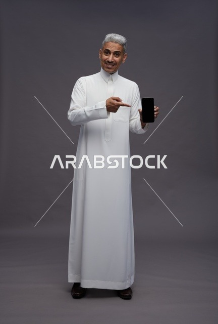 رجل سعودي يحمل هاتف ذكي في الاستوديو