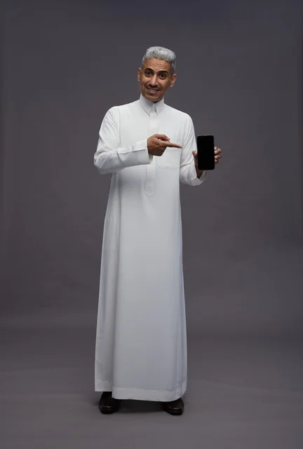 رجل سعودي يحمل هاتف ذكي في الاستوديو