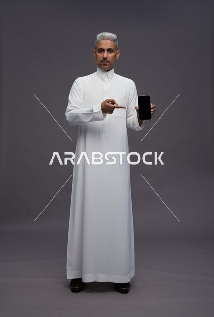 Saudi Man in Thobe Holding Smartphone Studio Shot