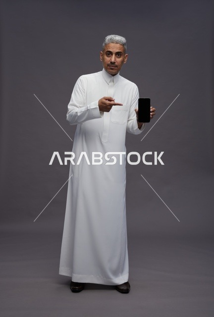 Saudi Man Holding Smartphone on Grey Background