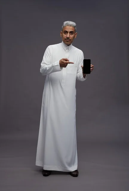 Saudi Man Holding Smartphone on Grey Background