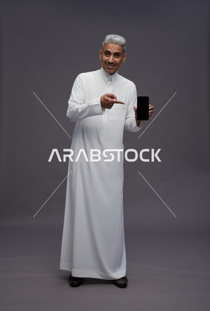 Saudi Man Holding Smartphone on Gray Background
