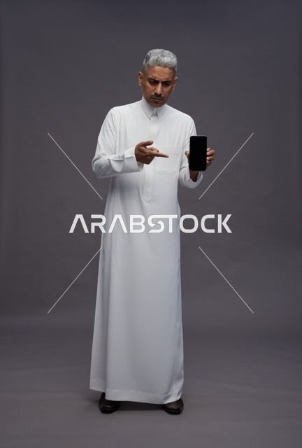 Saudi Man in White Thobe Holding Blank Smartphone Screen