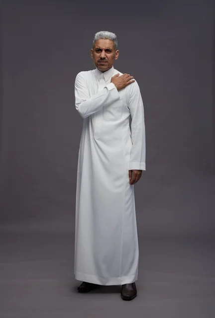 Saudi Man in Traditional White Thobe with Shoulder Pain