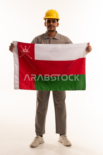 عامل بناء عماني ممسك بعلم سلطنة عمان