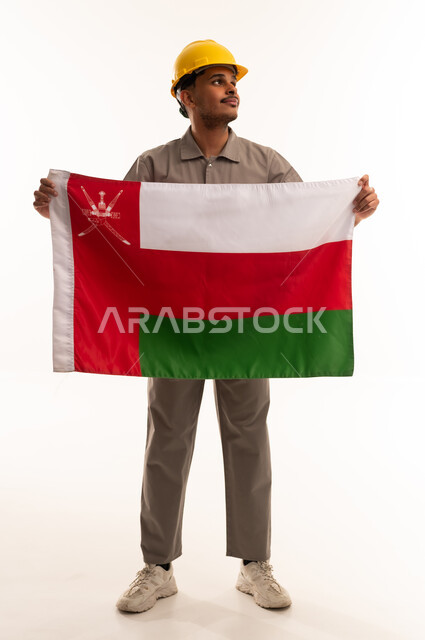 مهندس عماني يحمل علم سلطنة عمان بزي العمل