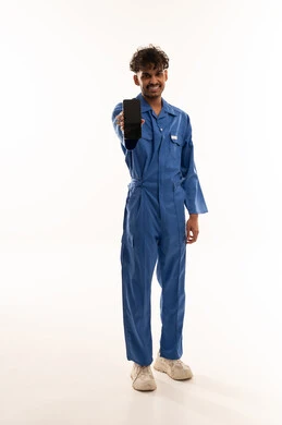 عامل هندي ببدلة زرقاء يحمل هاتفاً ذكياً