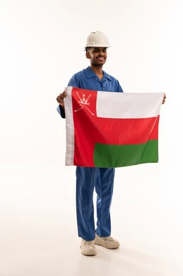 عامل عماني يرتدي خوذة السلامة ويحمل علم عمان