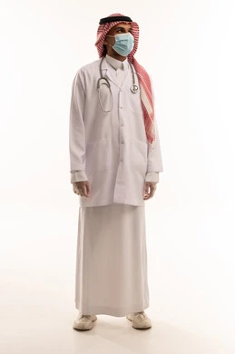 طبيب سعودي بالزي الطبي والكمامة أمام خلفية بيضاء